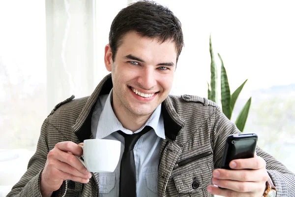 Gelukkig jonge zakenman met behulp van mobiele telefoon in zakelijke gebouw, — Stockfoto