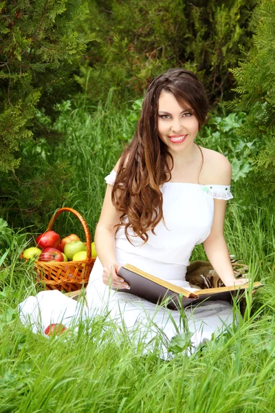 Una hermosa mujer sonriente leyó el libro sobre la naturaleza. jardín —  Fotos de Stock