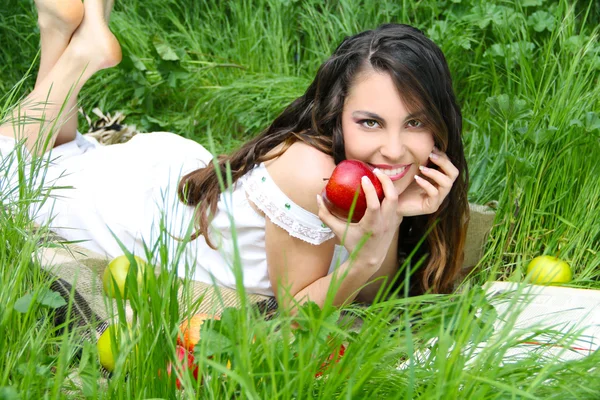 Happy smiling young women with red apple on the green field, out — Stock Photo, Image