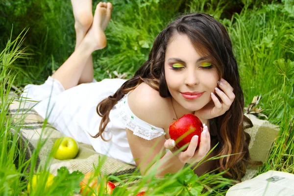 Jovens mulheres satisfeitas com maçã vermelha no campo verde, ao ar livre — Fotografia de Stock