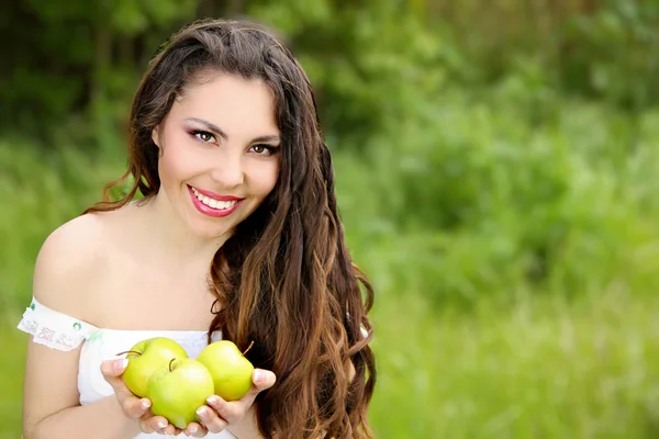 Hermosa mujer joven sosteniendo manzanas en la hierba al aire libre backgroun —  Fotos de Stock