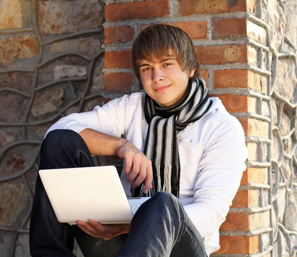 Tuğla duvara yaslanmış laptop ile genç adam — Stok fotoğraf