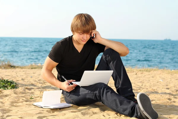 Casual jovem homem de negócios usando laptop na praia — Fotografia de Stock