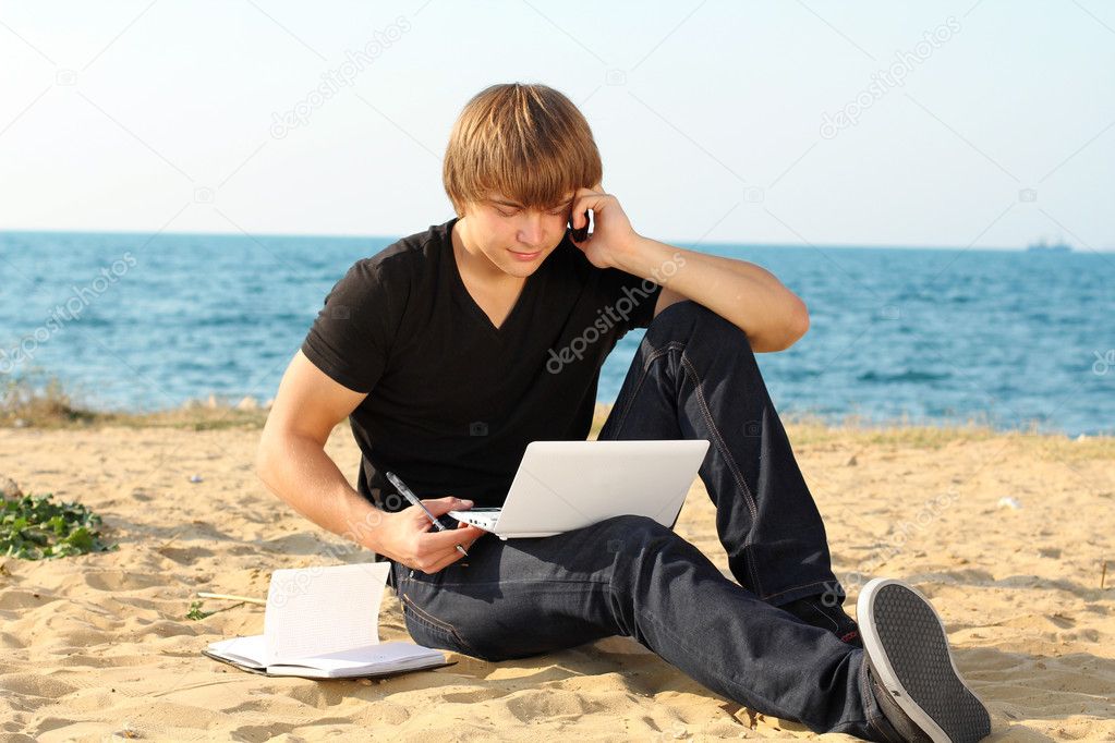 Casual young business man using laptop on the beach
