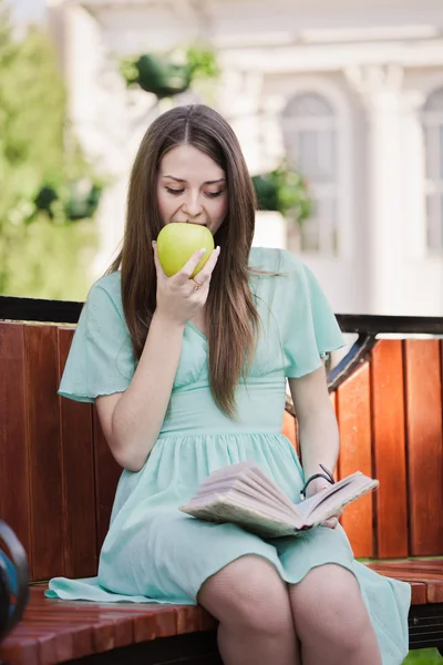 ผู้หญิงที่มีหนังสือและแอปเปิ้ลกลางแจ้ง — ภาพถ่ายสต็อก