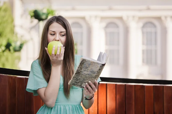 Девушка с книгой и яблоком на открытом воздухе — стоковое фото