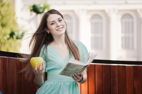 Девушка с книгой и яблоком на открытом воздухе — стоковое фото