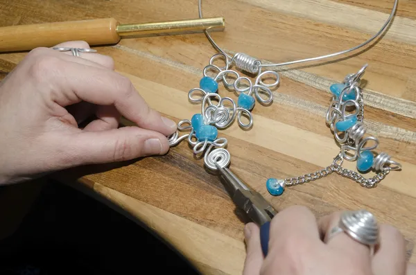Mãos de mulher criando uma jóia de moda Imagens De Bancos De Imagens