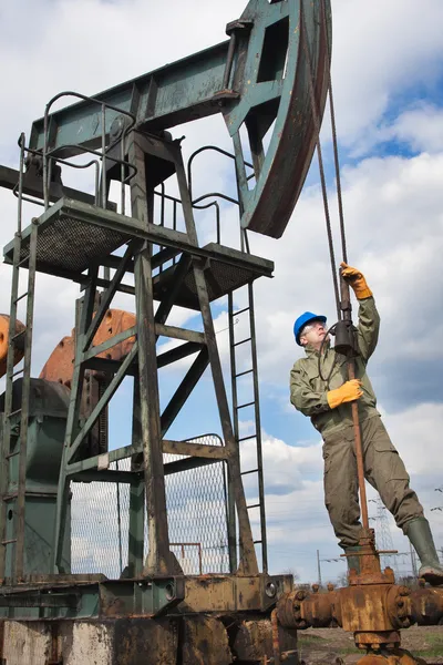 Работник нефтяной промышленности на нефтяном насосе — стоковое фото