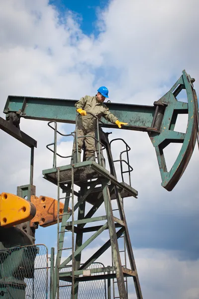 Работник нефтяной промышленности на нефтяном насосе — стоковое фото