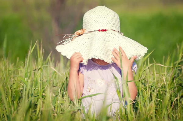 En vacker liten flicka med en hatt i ett korn fält — Stockfoto