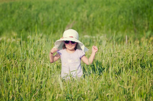 Uma menina bonita com um chapéu em um campo de grãos — Fotografia de Stock