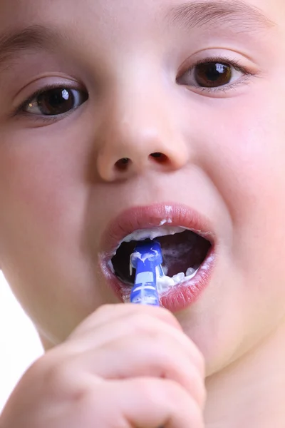 Un adorable niño pequeño cepillándose los dientes sobre fondo blanco — Foto de Stock