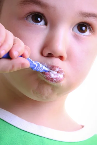 Un adorable niño pequeño cepillándose los dientes sobre fondo blanco — Foto de Stock