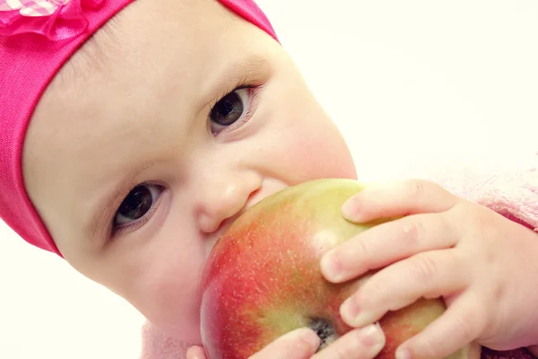 Bebé sosteniendo y comiendo una manzana, aislado en blanco — Foto de Stock