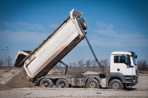 O caminhão branco descarregando areia no local — Fotografia de Stock