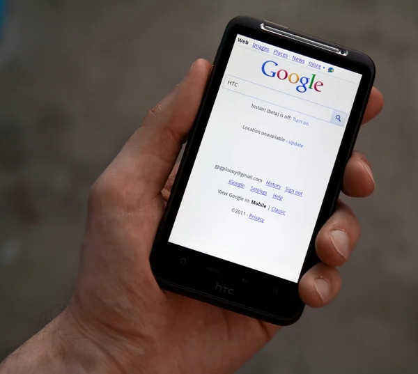 Hand hold HTC Desire HD with Google web page — Stock Photo, Image
