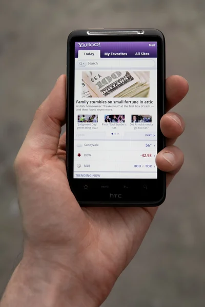 Mão segurando HTC Desejo HD mostrando Yahoo notícias — Fotografia de Stock