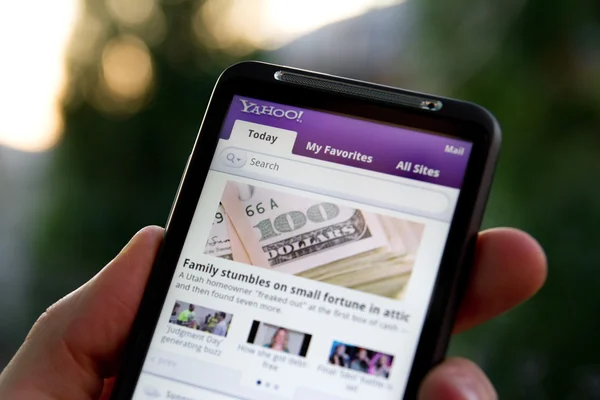 Mão segurando HTC Desejo HD mostrando Yahoo notícias — Fotografia de Stock