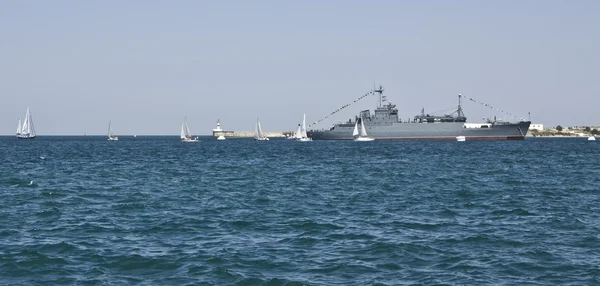 Military ship and littls sailing boats — Stock Photo, Image