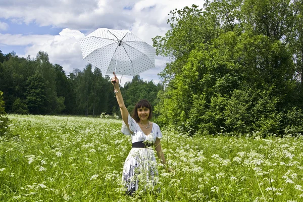 Jonge vrouw met witte paraplu op weide in bloei — Stockfoto