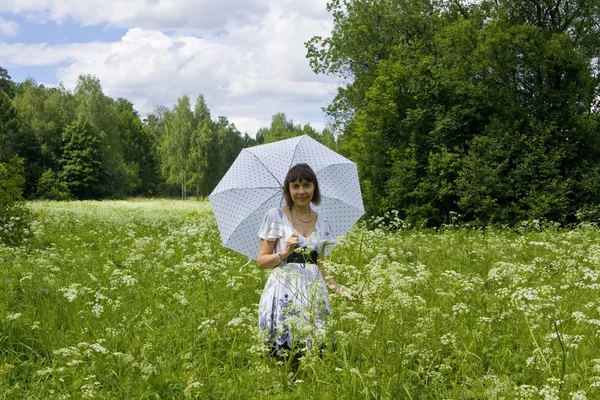 Jovem com guarda-chuva branco no prado em flor — Fotografia de Stock