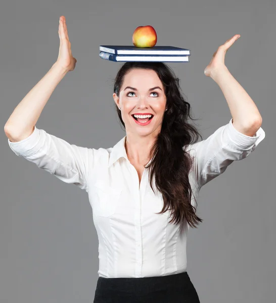 Vrouw evenwicht tussen apple en boeken op hoofd — Stockfoto