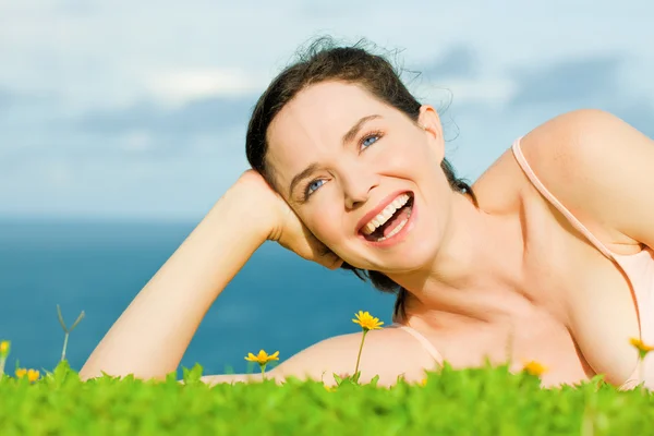 Beautiful happy laughing woman lying in green grass — Stock Photo, Image