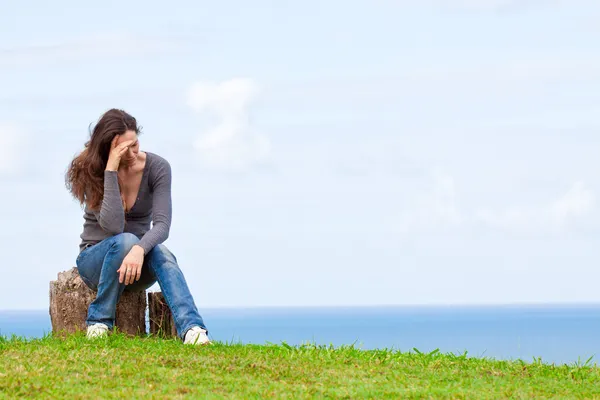 郁闷、 悲伤和沮丧的年轻女子坐在外面 图库照片