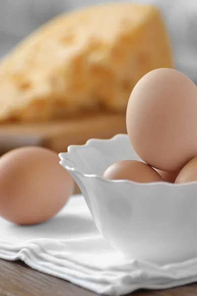 Chicken eggs in white dish with cheese on a wooden table — Stock Photo, Image