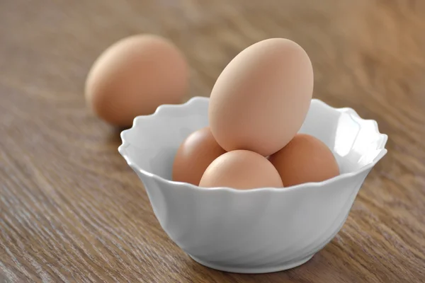 Куриные яйца в белом блюде с сыром на деревянном столе — стоковое фото