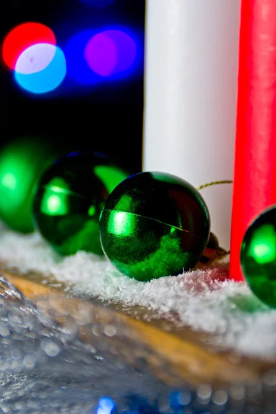 Kırmızı ve beyaz mum ışıkları arka plan üzerinde yeşil bir yeni yıl top ile — Stok fotoğraf