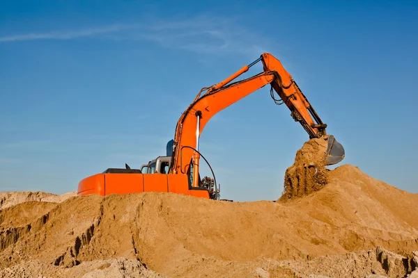 Экскаватор работает в песочнице, перемещая землю — стоковое фото