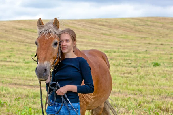 牧草地で彼女の馬を持つ少女 — ストック写真