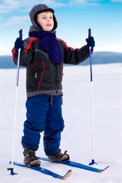 Glimlachend kind jongen skiër permanent in sneeuw — Stockfoto