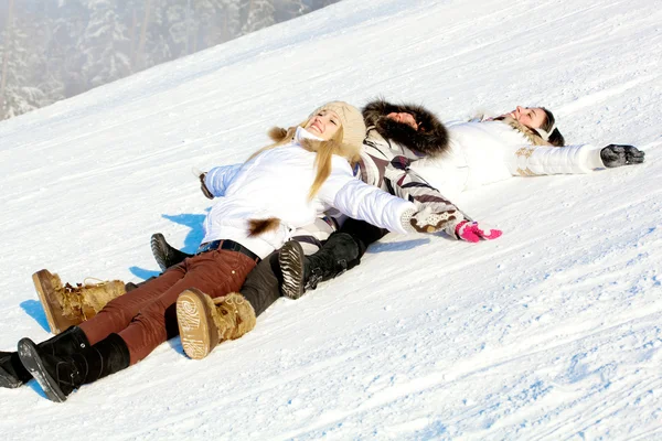 Giovani ragazze positive sdraiate sulla neve — Foto Stock