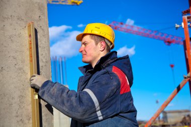Construction worker checking vertical level of house wall clipart