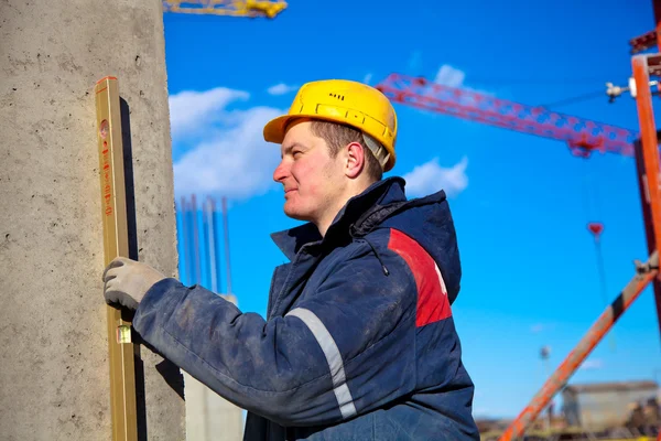 Construction worker checking vertical level of house wall — Stock Photo, Image