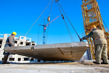 Industrial workers unloading concrete plate from crane clipart