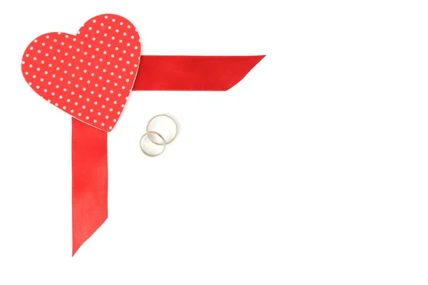 Red satin ribbon with heart and wedding rings — Stock Photo, Image