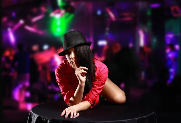 ナイトクラブでテーブルの上に横たわるの帽子、セクシーな女性 — ストック写真