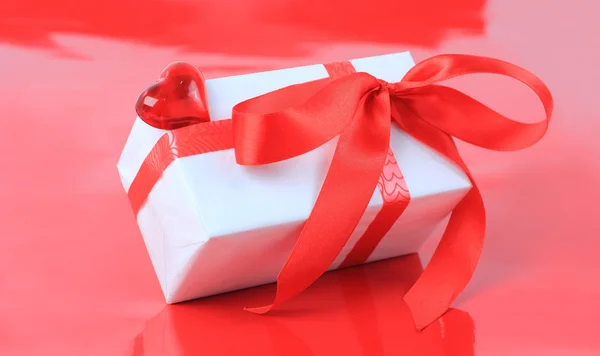 White box, bow, and ribbon for Valentine's Day or other events on red — Stock Photo, Image