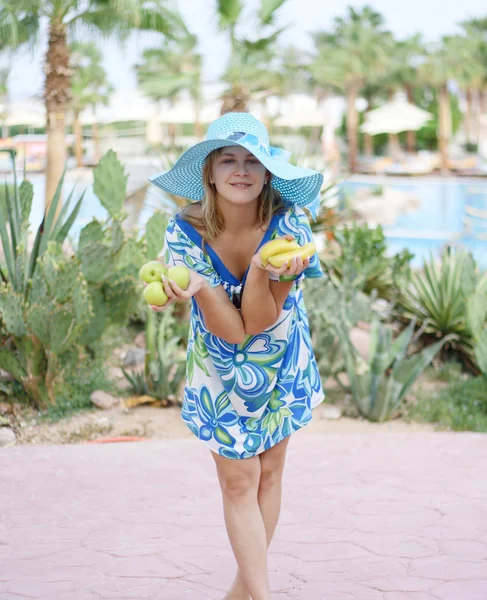 Foto de una hermosa joven en un sombrero con manzanas frescas y plátanos en sus manos — Foto de Stock