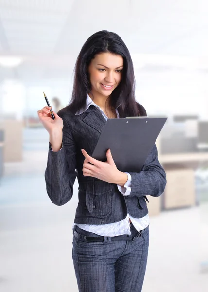 Sorrindo mulher de negócios escrevendo em prancheta em seu escritório — Fotografia de Stock