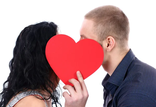 Glückliches Paar küsst sich hinter einem roten Herzen — Stockfoto