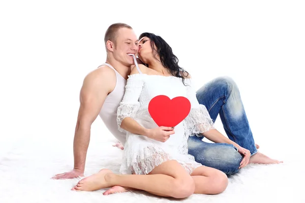 快乐年轻成人夫妇与地板上红色的心 — 图库照片