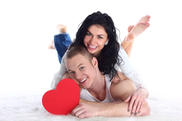 Молодая взрослая пара с красным сердцем лежит на полу — стоковое фото