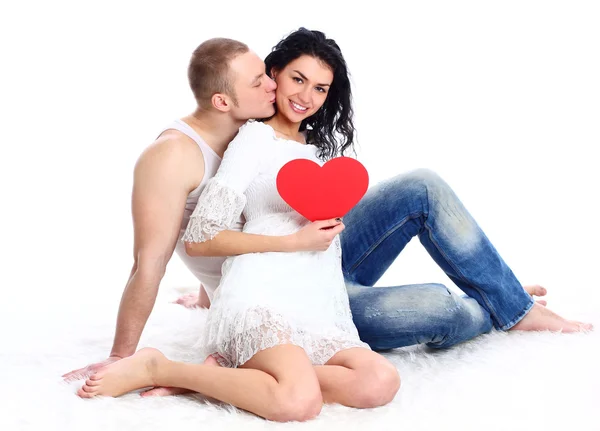 Mladý dospělý pár s červeným srdcem na podlaze — Stock fotografie