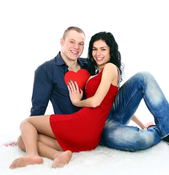 Happy young adult couple with red heart on the floor — Stock Photo, Image