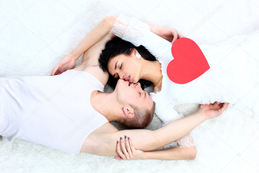 Couple holding red heart together lying
